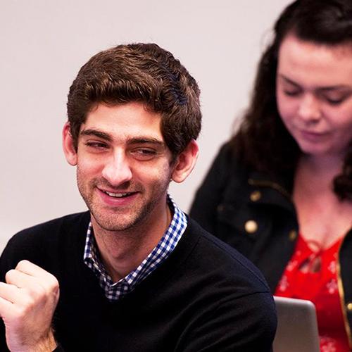 A student sits in class and smiles.