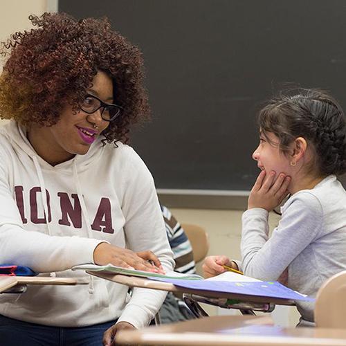 A student teacher works with a young student.