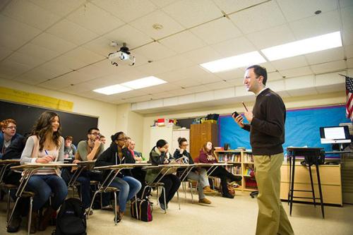 A male professor teaches at the front of the class.