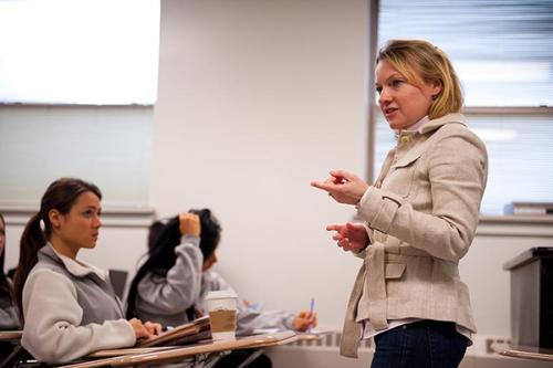 A female professor teaches at the front of the class.